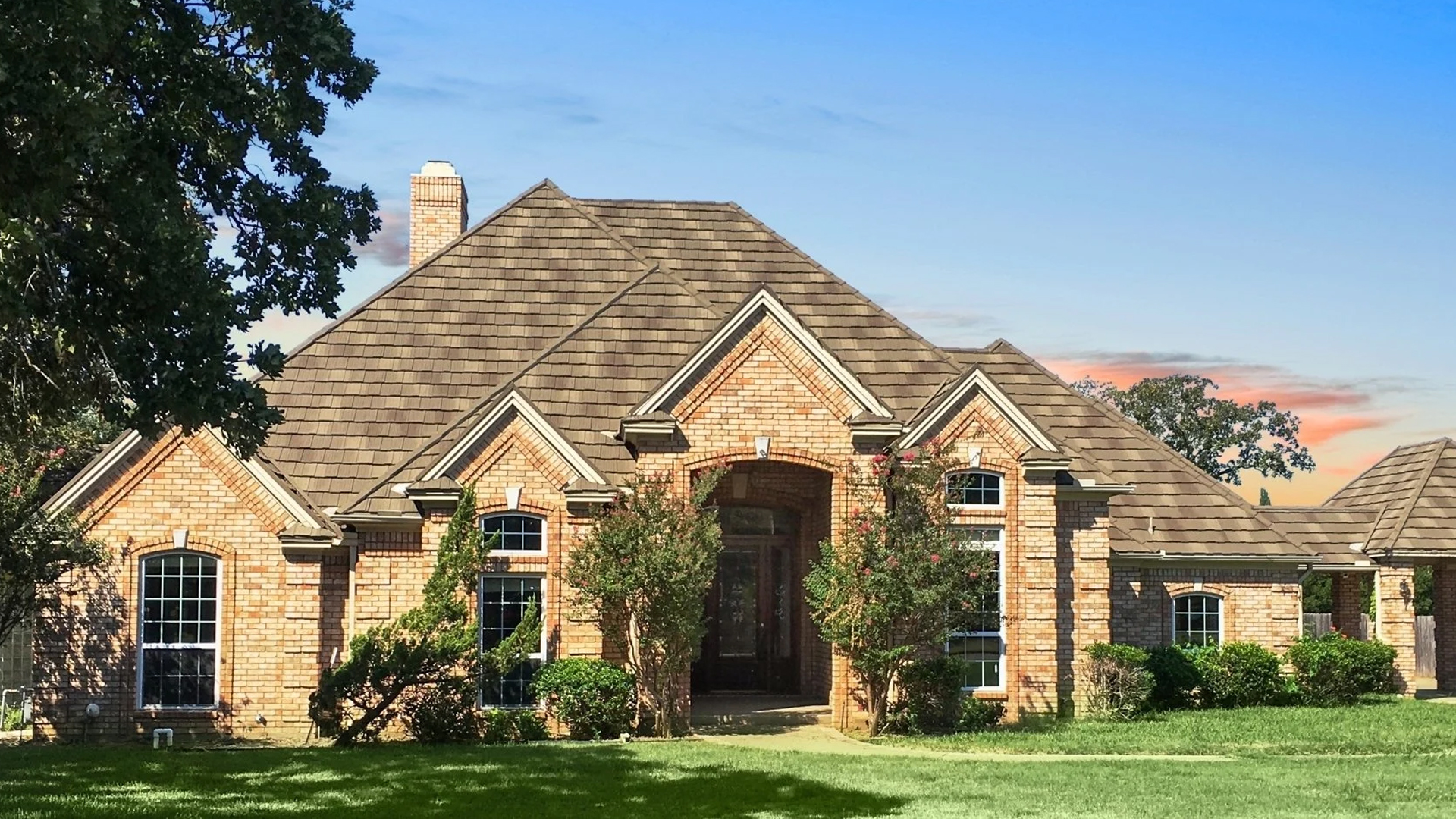 A DECRA Shake XD roof (DECRA product photo) A brick house with a DECRA Shake XD stone-coated steel roof