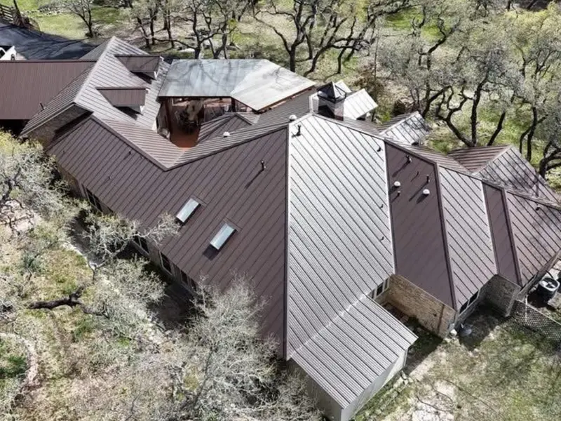 Two-tone standing seam metal roof on a home surrounded by oak trees